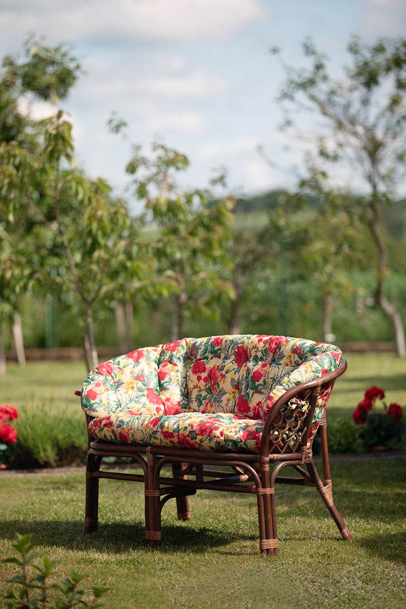 sofa rattanowa w ogrodzie kwiatowe poduszki